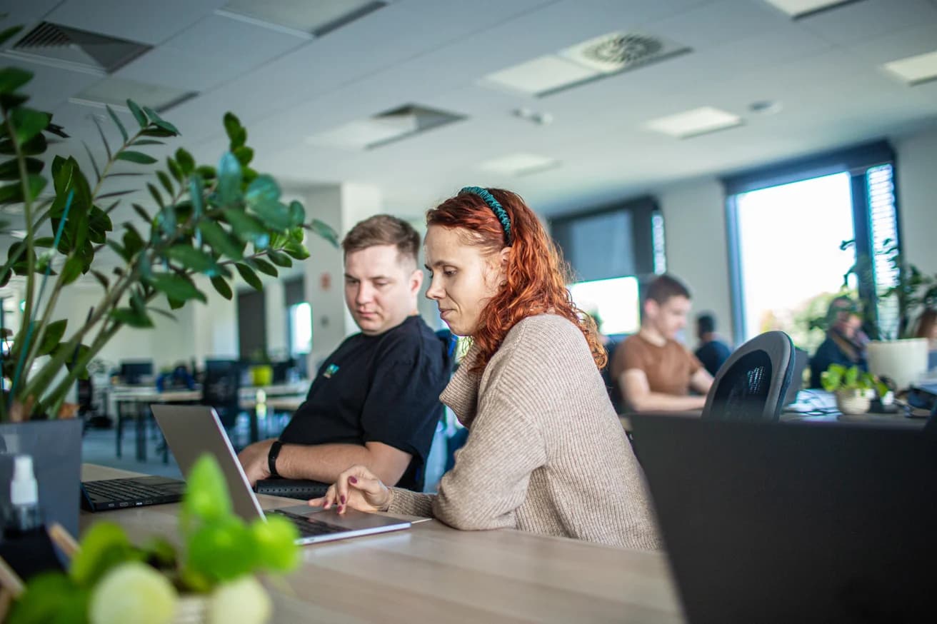 Two people from the Pragmatic Coders team working at a laptop